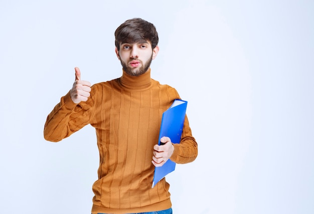 Foto gratuita el hombre con una carpeta azul parece poderoso y satisfecho.