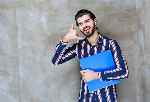 Hombre con una carpeta azul que muestra el distintivo de llamada.