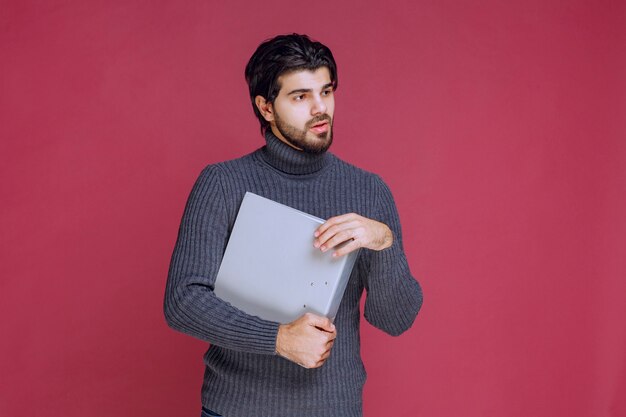 Hombre con carpeta gris discutiéndolo con los colegas mientras revisa.