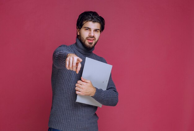 Hombre con carpeta gris discutiéndolo con los colegas mientras revisa.