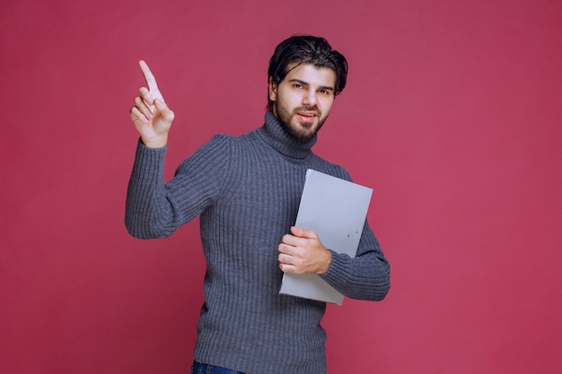 El hombre con la carpeta gris hace que su dedo índice hacia arriba.