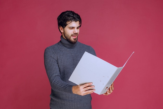 Hombre con carpeta gris leyendo los informes.