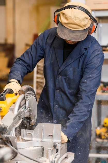 Foto gratuita hombre carpintero usando algunas herramientas eléctricas para su trabajo en una carpintería