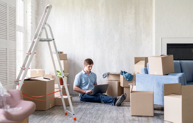 Hombre en casa con cajas y escalera preparándose para mudarse