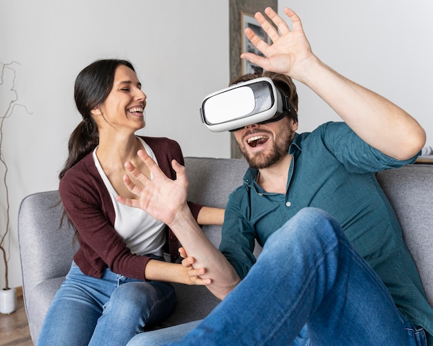 Foto gratuita hombre en casa divirtiéndose con casco de realidad virtual junto a la mujer