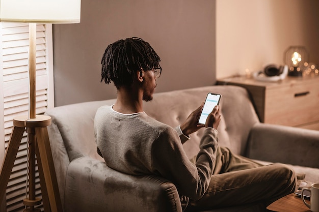 Foto gratuita hombre en casa en el sofá con smartphone