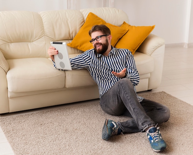 Hombre en casa con tableta junto al sofá