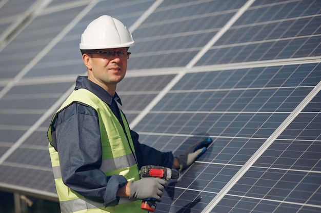 Foto gratuita hombre con casco blanco cerca de un panel solar