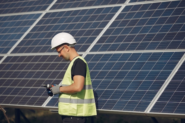 Hombre con casco blanco cerca de un panel solar