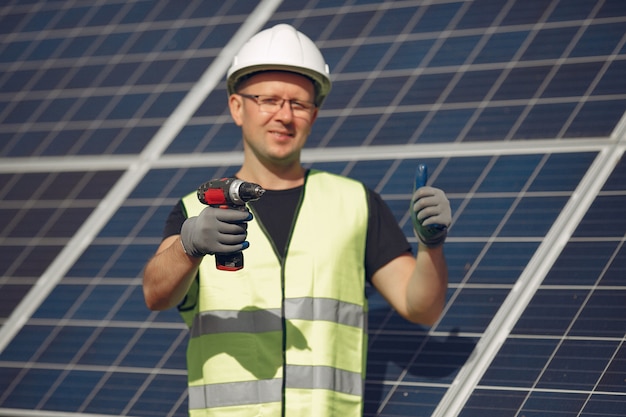 Hombre con casco blanco cerca de un panel solar