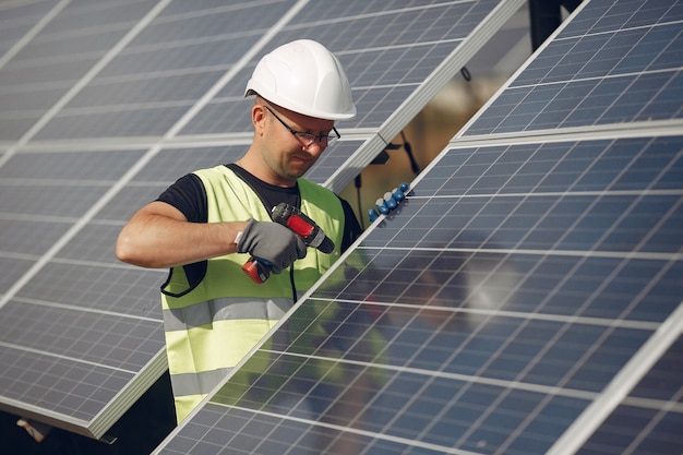 Hombre con casco blanco cerca de un panel solar