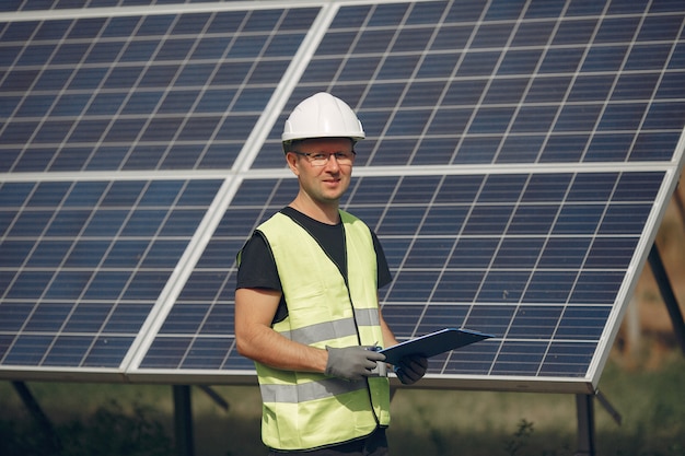 Hombre con casco blanco cerca de un panel solar