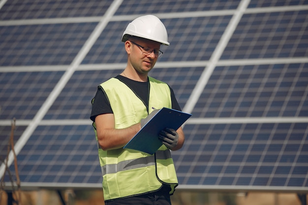 Hombre con casco blanco cerca de un panel solar