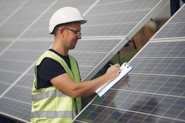 Foto gratuita hombre con casco blanco cerca de un panel solar