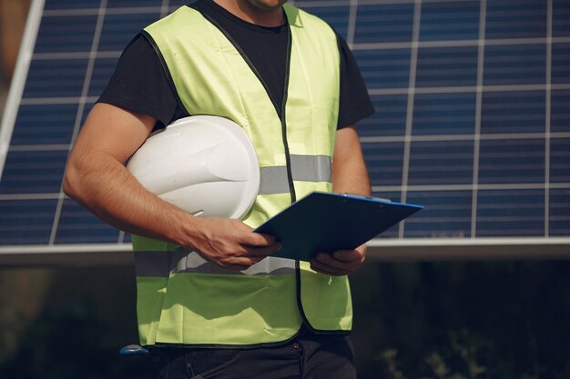 Hombre con casco blanco cerca de un panel solar