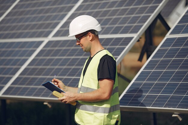 Hombre con casco blanco cerca de un panel solar