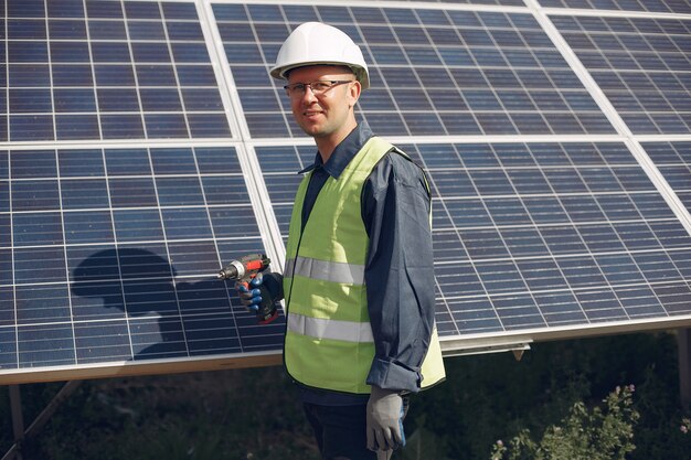 Hombre en un casco blanco cerca de un panel solar
