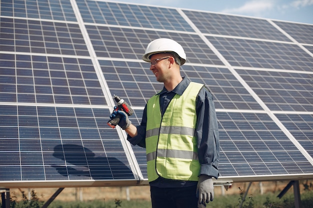 Hombre en un casco blanco cerca de un panel solar