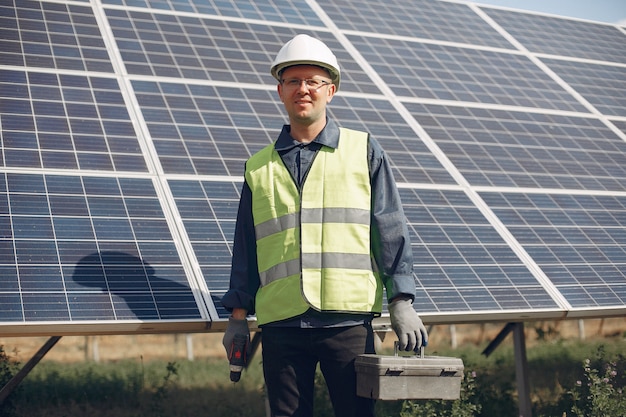 Hombre en un casco blanco cerca de un panel solar