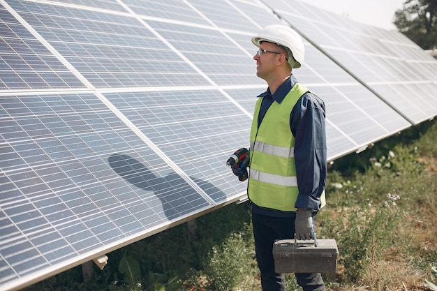 Hombre en un casco blanco cerca de un panel solar