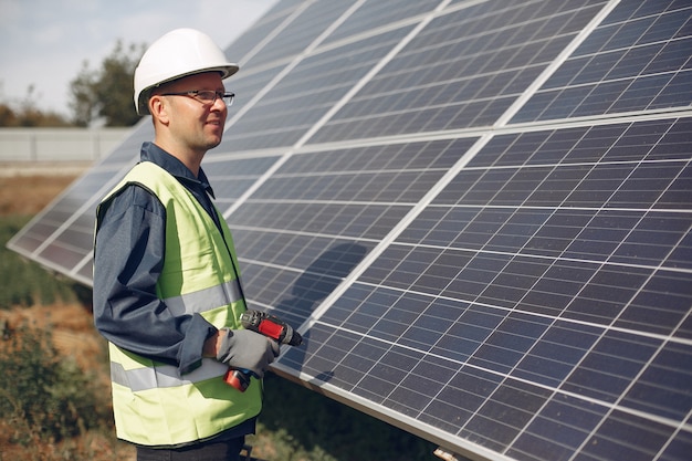 Hombre en un casco blanco cerca de un panel solar