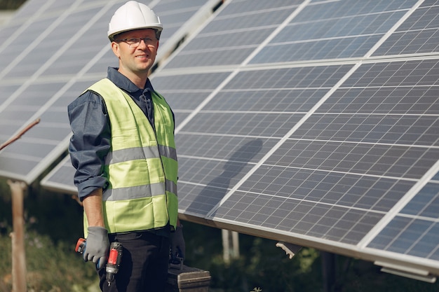 Hombre en un casco blanco cerca de un panel solar