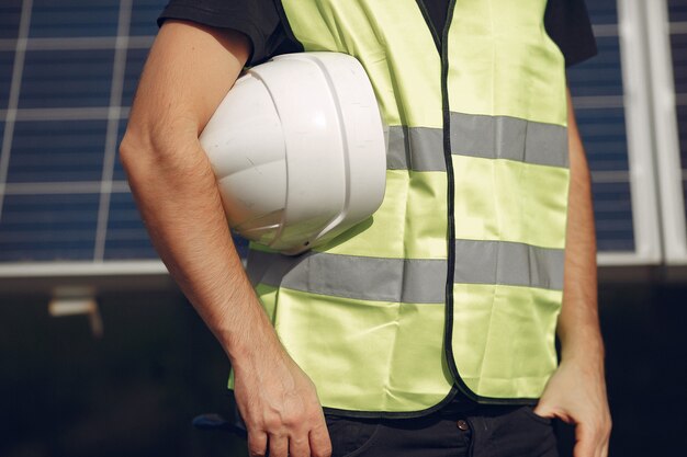 Hombre en un casco blanco cerca de un panel solar