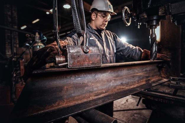 El hombre con casco está moviendo un trozo de riel en la fábrica de metal.