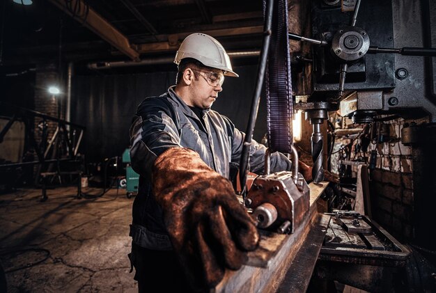 El hombre con casco está moviendo un trozo de riel en la fábrica de metal.