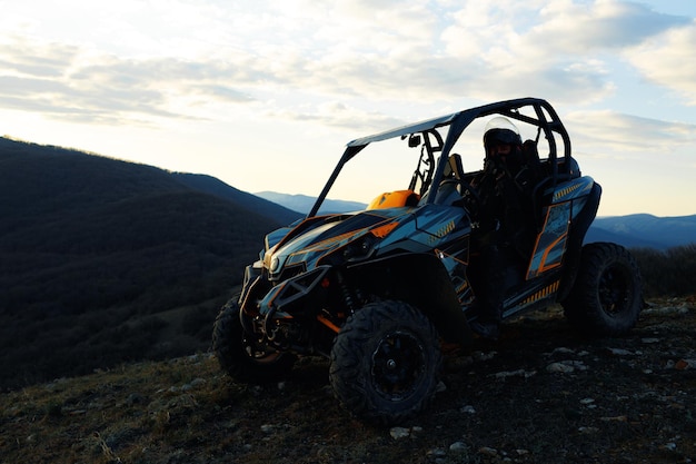 Hombre en casco sentado en quad atv en las montañas