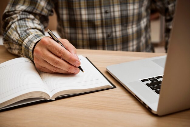 Hombre casual escribiendo en cuaderno en blanco