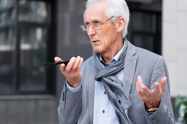 Hombre casual mayor en la ciudad hablando por teléfono inteligente