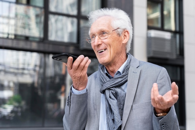 Hombre casual mayor en la ciudad hablando por teléfono inteligente