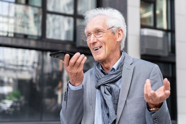 Hombre casual mayor en la ciudad hablando por teléfono inteligente