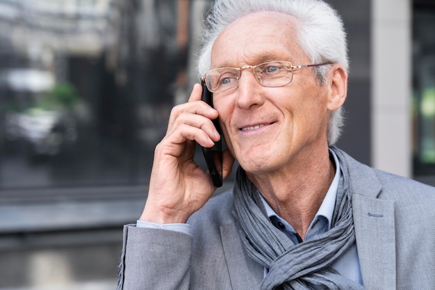 Hombre casual mayor en la ciudad hablando por teléfono inteligente