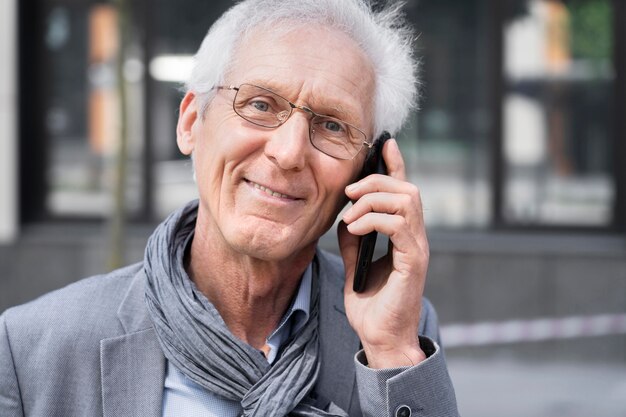 Hombre casual mayor en la ciudad hablando por teléfono inteligente
