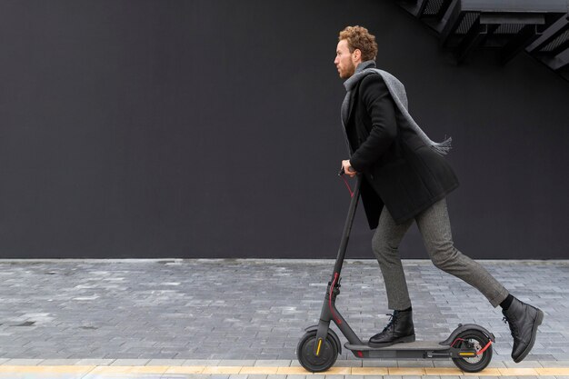 Hombre casual montando con su scooter eléctrico