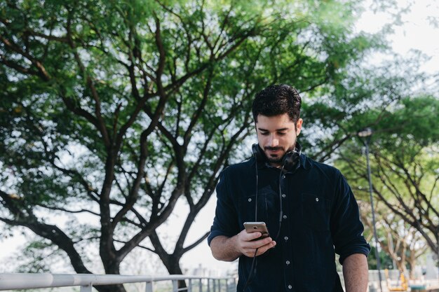 Hombre casual, navegar por el teléfono en el parque