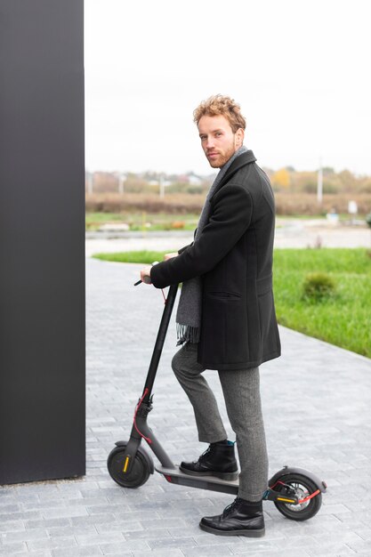 Hombre casual posando con un scooter eléctrico