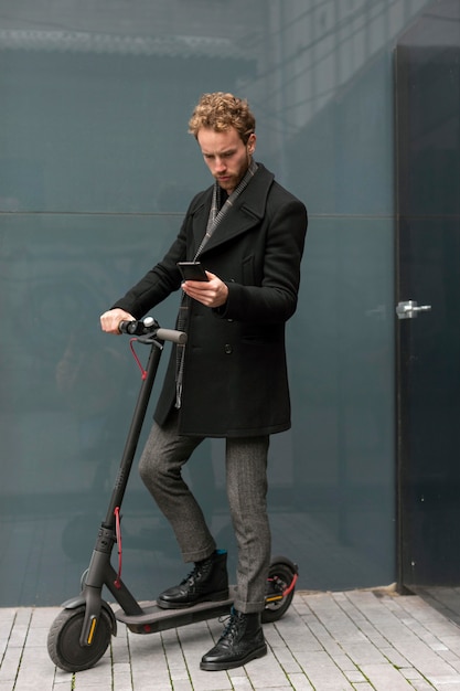 Hombre casual posando con un scooter eléctrico