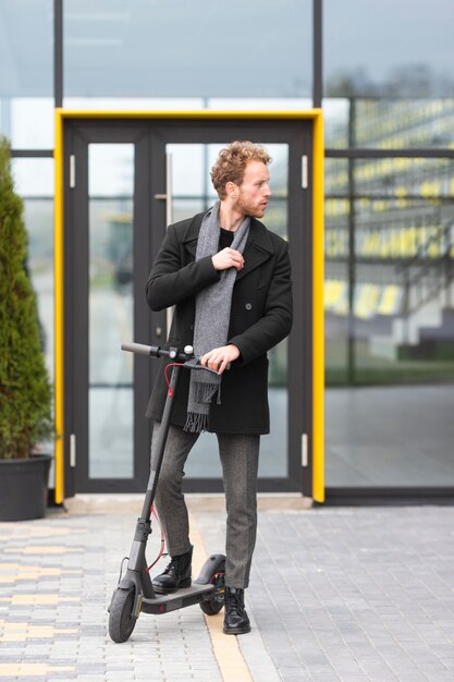 Hombre casual posando con un scooter eléctrico