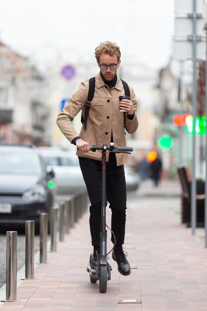 Hombre casual posando con un scooter eléctrico