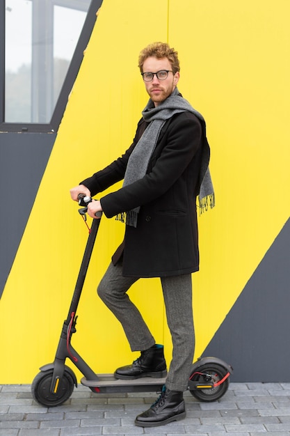 Hombre casual posando con un scooter eléctrico