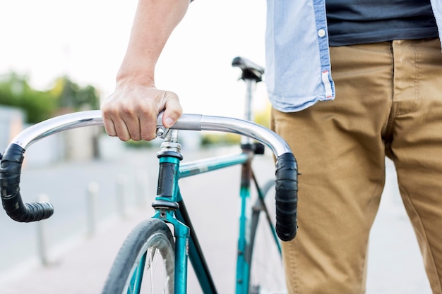 Hombre casual de primer plano sosteniendo su bicicleta