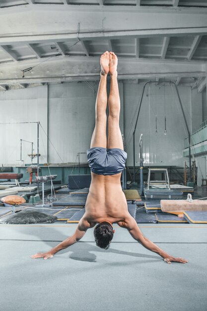 Hombre caucásico acrobacia gimnástica postura de equilibrio en el gimnasio