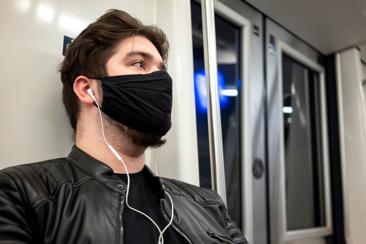 Foto gratuito un hombre caucásico con barba y auriculares en máscara médica negra en metro