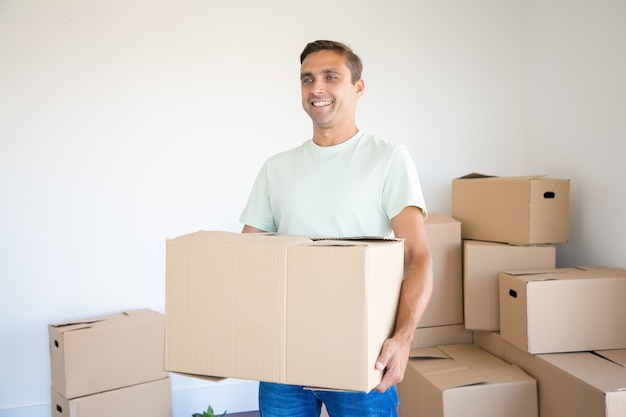 Hombre caucásico con caja de cartón en su nueva casa o apartamento