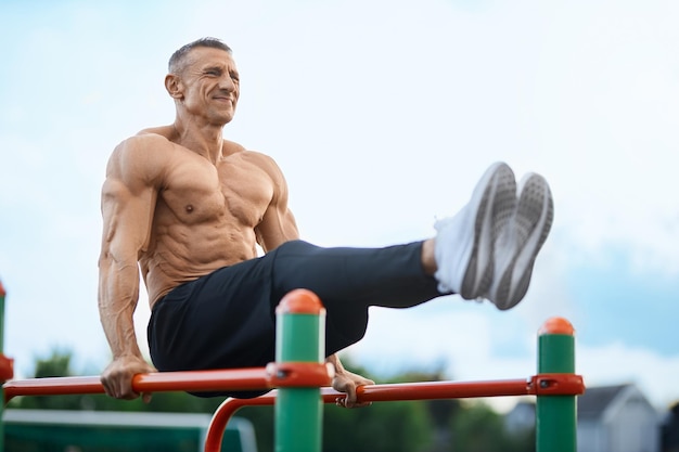 Hombre caucásico deportivo entrenando en barras paralelas al aire libre