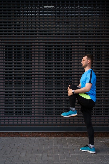 Hombre caucásico estiramiento mientras entrenamiento de la ciudad