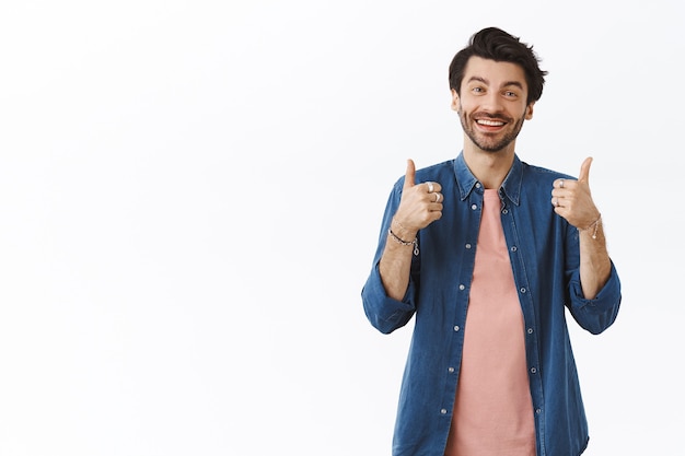 Hombre caucásico guapo complacido y amistoso en traje casual que muestra el pulgar hacia arriba como califica algo bueno, sonriendo y asiente con la cabeza, da una retroalimentación positiva, pensando que algo es excelente